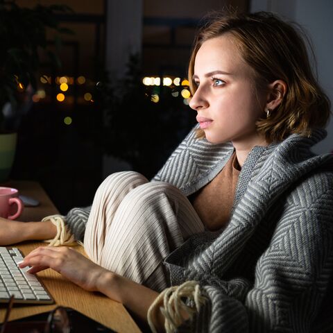 Un'adolescente è seduta a casa al buio davanti al computer.