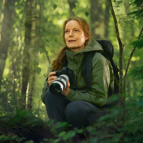 Eine Frau mit einer Kamera im Wald