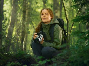 Eine Frau mit einer Kamera im Wald