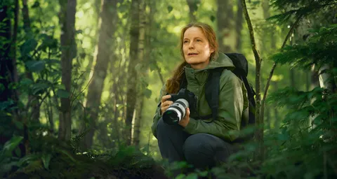 Eine Frau mit einer Kamera im Wald
