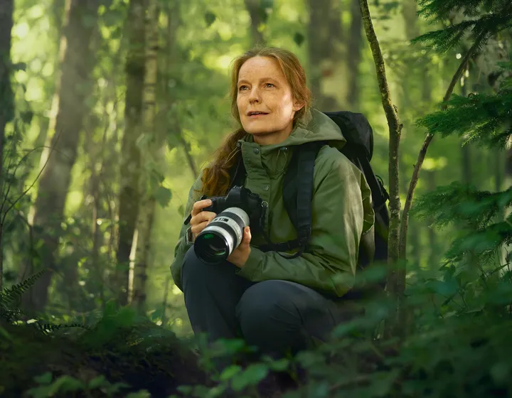 Une femme avec un appareil photo dans la forêt