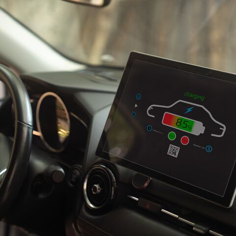 The screen in a car displays an image of a car with the charge indicator at 85% and the word “Charging” written in green letters.