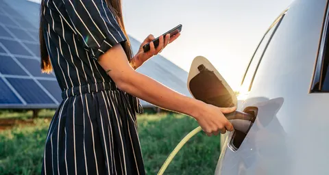 Une femme recharge sa voiture électrique