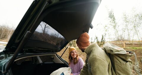 Une femme et un homme sortent vos bagages du coffre et se mettent à rire.
