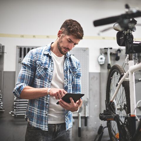 Un giovane con un tablet in mano in un negozio di biciclette