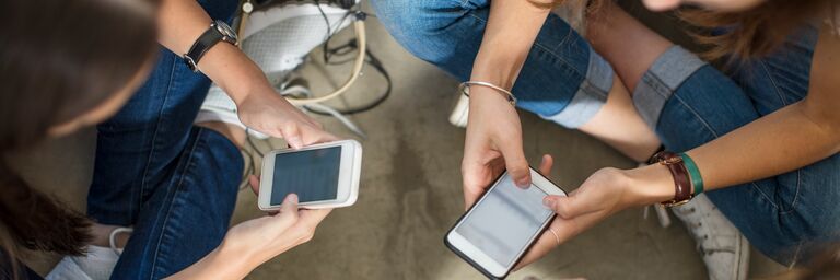 Tre persone sono sedute in cerchio e stanno parlando al cellulare.