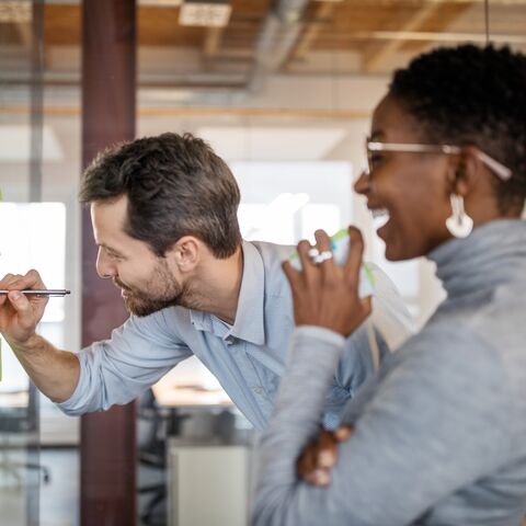 Two employees are happily standing in front of a flipchart.