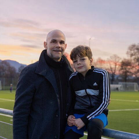 Un père et son fils. Ils sont assis au bord d’un terrain de football.