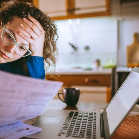 A young woman looks at a bill with concern.