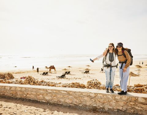 Zwei Frauen auf einer Reise in Marokko stehen auf einem Mäuerchen.