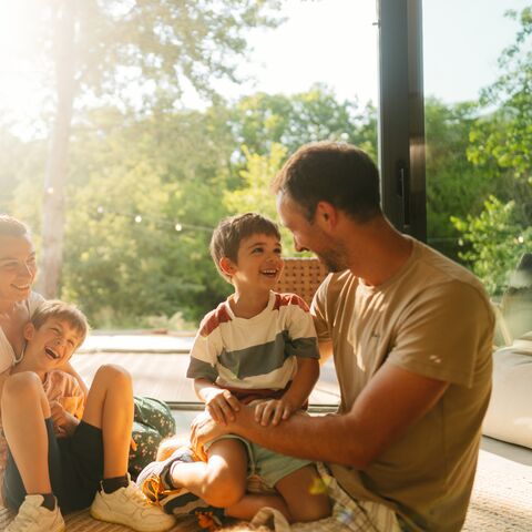 Une famille assise dans son salon rit.