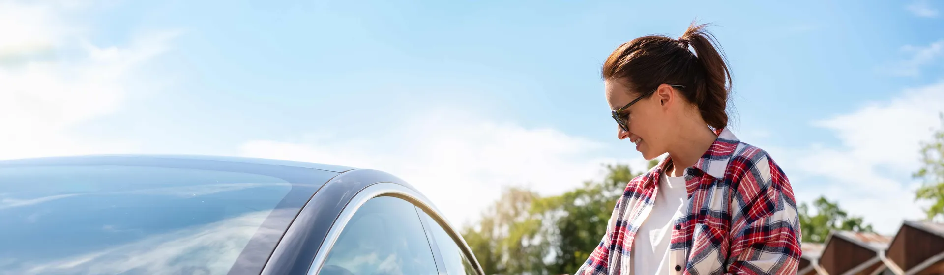 Eine junge Frau öffnet ihr parkiertes Auto.