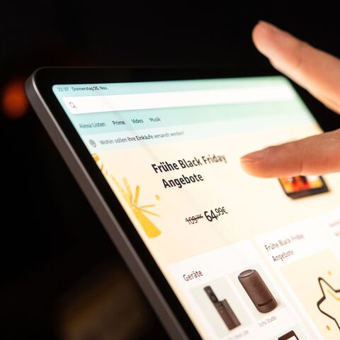 Une main appuie sur l’écran d’une tablette affichant un site Web proposant des offres précoces et des prix réduits pour le Black Friday.