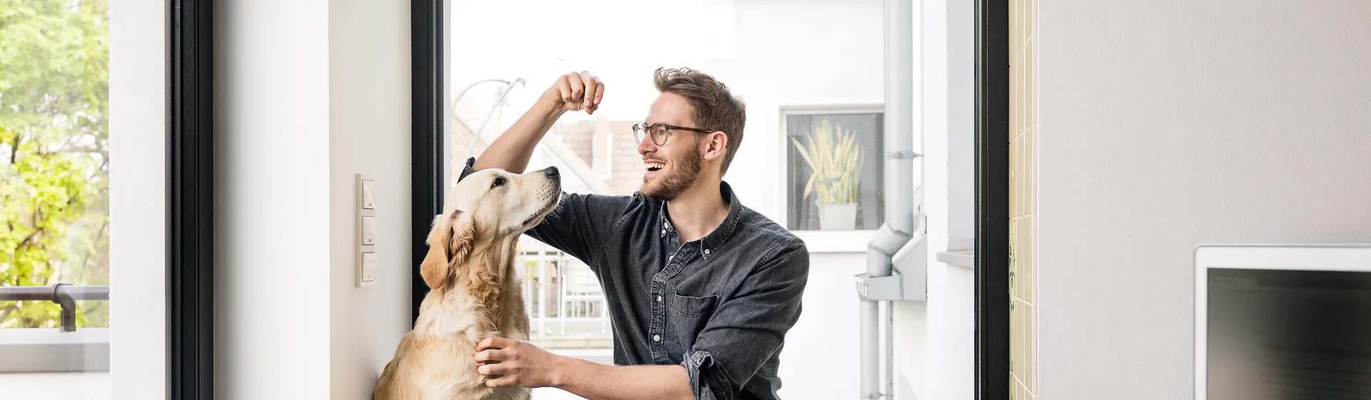 Un uomo è seduto per terra con il suo cane e gli dà un bocconcino.