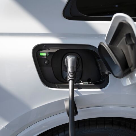 Une voiture électrique est chargée à une borne de recharge à l’aide du câble branché dans la prise située sur le côté gauche du véhicule.