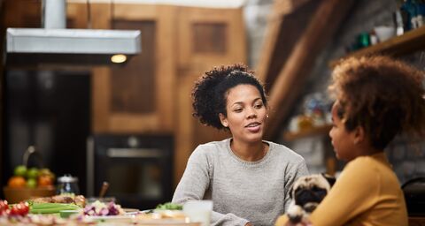 Une mère est assise à table avec sa fille et leur chien.