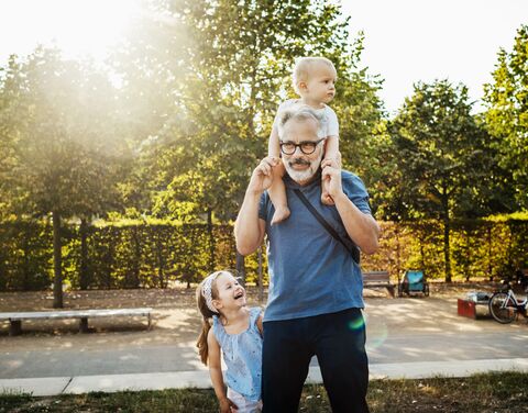 A grandfather is outside with his two grandchildren.