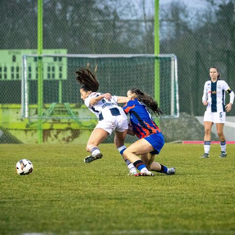 Zwei Fussballerinnen kämpfen auf dem Spielfeld um den Ball.