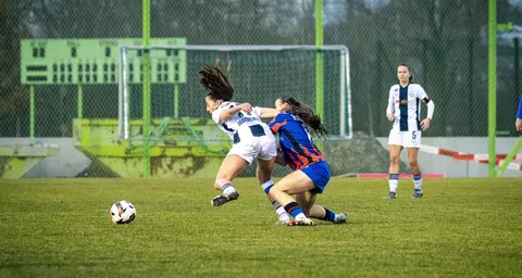 Deux footballeuses s’affrontent pour le ballon sur le terrain.