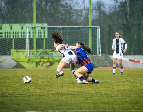 Zwei Fussballerinnen kämpfen auf dem Spielfeld um den Ball.