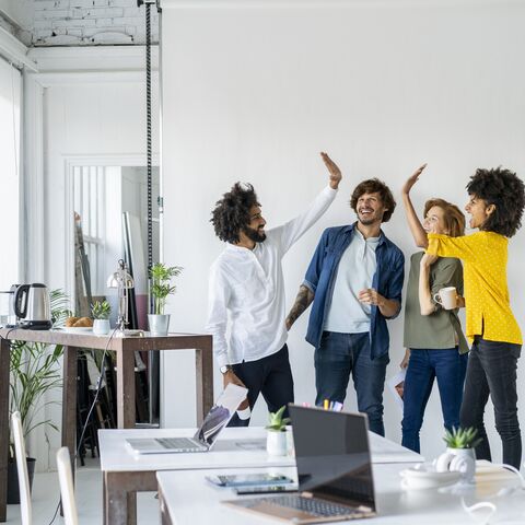 Junge Unternehmen stehen im Büro und geben sich High Five
