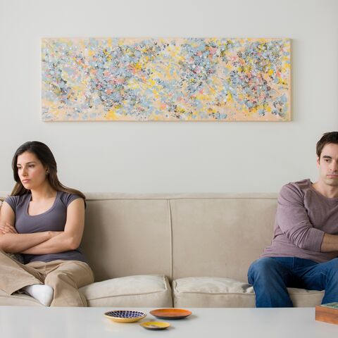 Une femme et un homme sont assis éloignés l’un de l’autre sur un canapé et regardent dans des directions opposées.