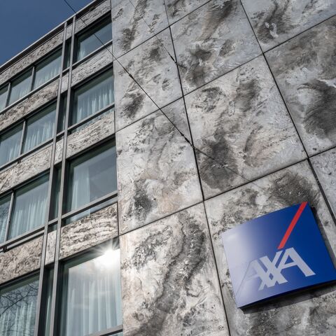 Ein modernes Bürogebäude ragt in den blauen Himmel. Die schieferartige Fassade mit dem AXA-Logo schimmert im Sonnenlicht.