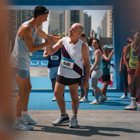 Ein junger Läufer gratuliert einem älteren Läufer bei einem Stadtmarathon.
