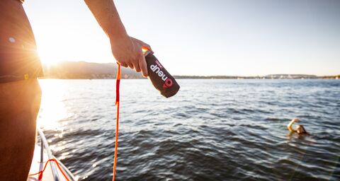 A woman is in the water and needs help. Her girlfriend throws her a new, compact lifebuoy.