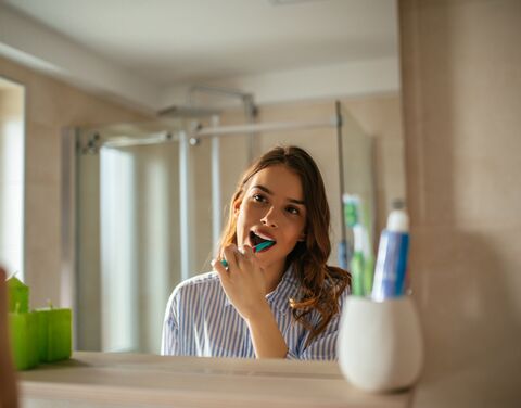 Une jeune femme se brosse les dents.