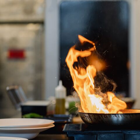 Sur la cuisinière se trouve une poêle en feu.