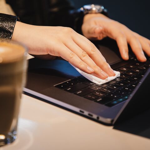 Une personne nettoie/désinfecte son ordinateur portable.