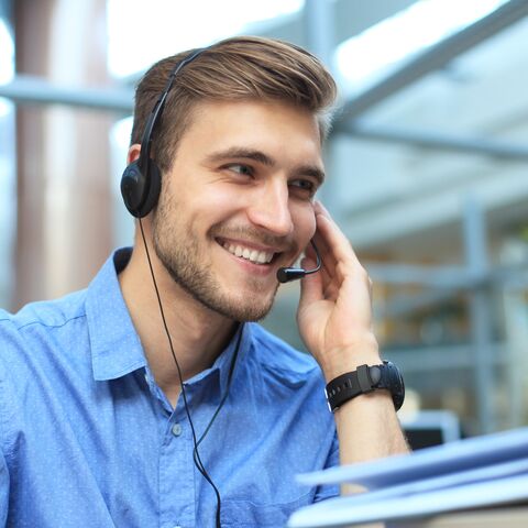 Un représentant du service à la clientèle souriant amicalement enregistre la demande d’un client.