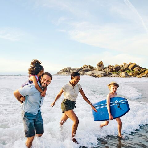 A family runs out of the water and laughs.