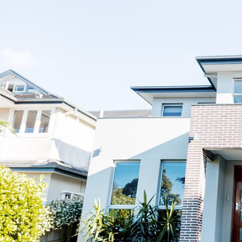 Un couple se tient devant une maison moderne de deux étages avec de grandes fenêtres et s'embrasse tout en admirant la maison.