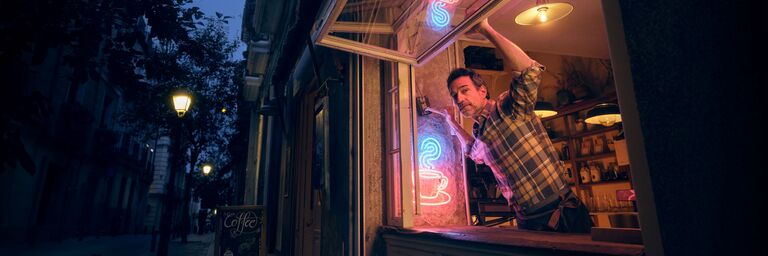 Self-employed man looks out from his café