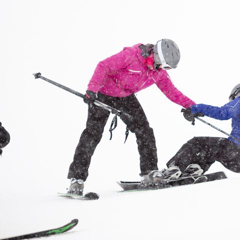 A skier helps her fallen colleague on her feet.
