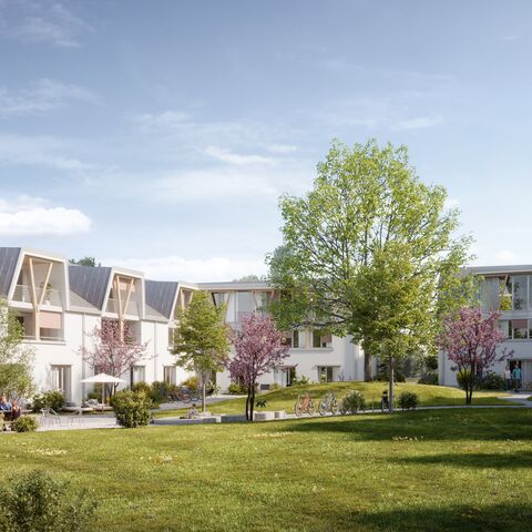 Ein moderner Wohnkomplex mit drei Stockwerken, begrüntem Innenhof, bunten Bäumen, Fahrradständern und Sitzgelegenheiten unter einem blauen Himmel.