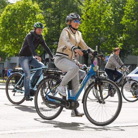 An older couple riding their e-bikes across an intersection.