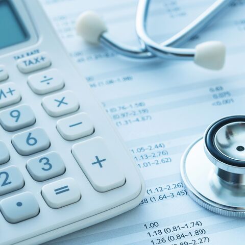 A calculator and a stethoscope are placed on a financial document showing medical expenses and charges.