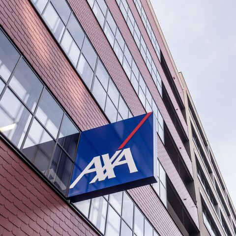 Ein modernes Bürogebäude mit roten Ziegeln und grossen Fenstern, an dem ein blaues AXA-Logo mit weisser Schrift und rotem Streifen angebracht ist.