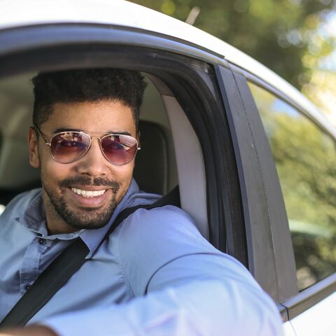 Ein Mann mit einer Sonnenbrille sitzt im Auto.