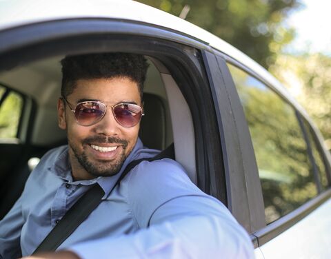 Ein Mann mit einer Sonnenbrille sitzt im Auto.
