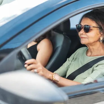 Ältere Autofahrerin mit angelegtem Sicherheitsgurt fährt sicher im Strassenverkehr.