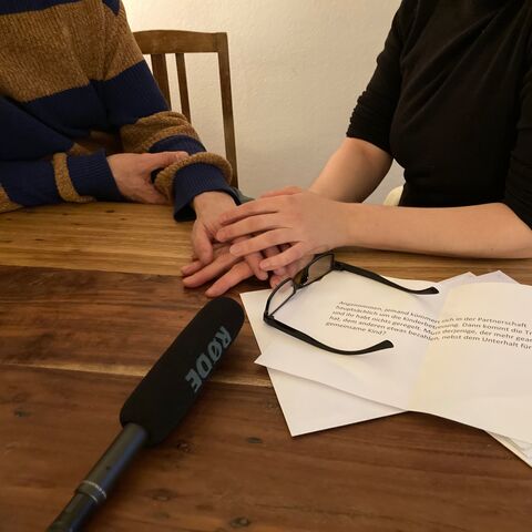 Aufnahme während des Podcasts mit den Personen, die sich über das Mikrofon austauschen und sich Notizen machen.