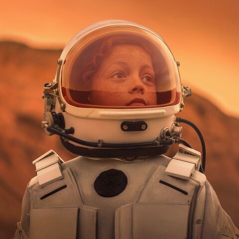 Une petite fille en costume d’astronaute. Son regard est tourné vers l’avenir.