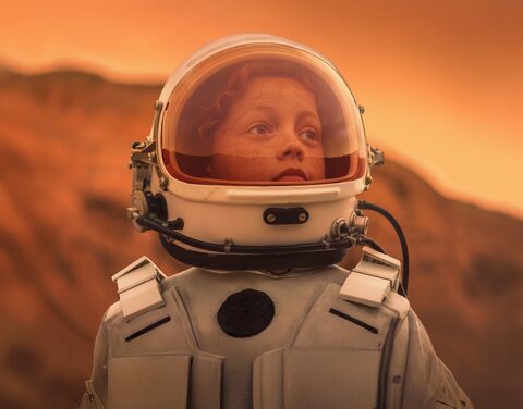 Ein junges Mädchen in einem Astronautenanzug. Sie blickt in die Zukunft.