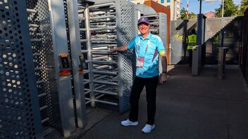 Un collaboratore di AXA indossa la Volunteer Shirt davanti al tornello dello stadio.