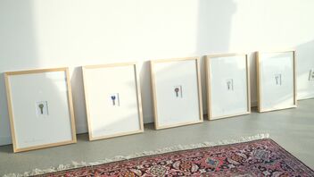Fünf Bilderrahmen mit jeweils einem Schlüssel stehen auf dem Boden vor einer weissen Wand. Im Vordergrund liegt ein rotgemusterter Teppich.