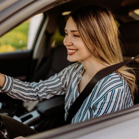 Junge Frau sitzt angeschnallt im Auto.